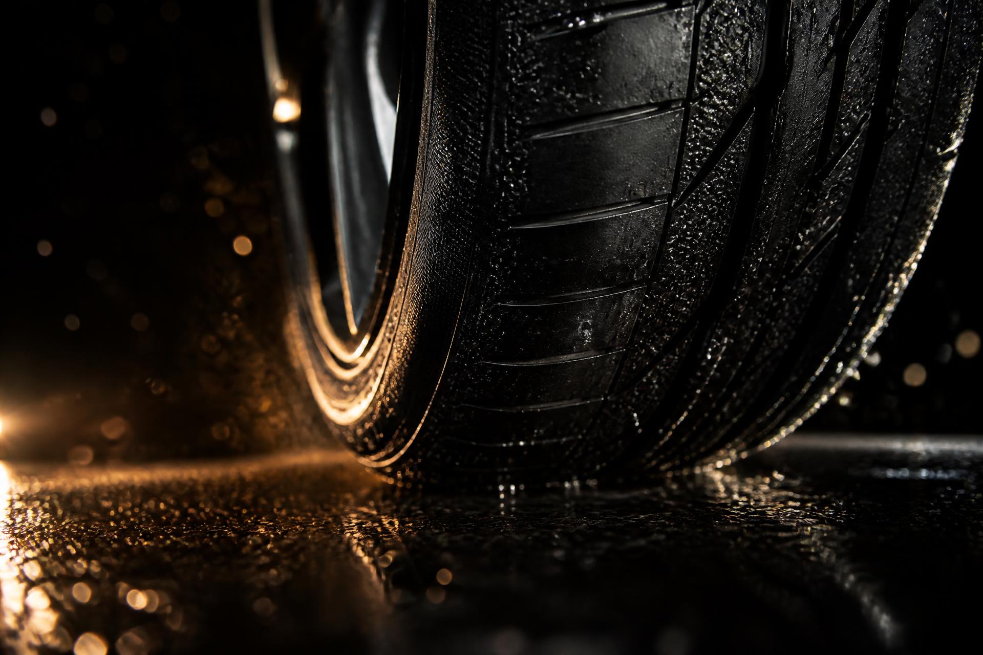 Close-up of a performance tire tread gripping wet asphalt under warm light